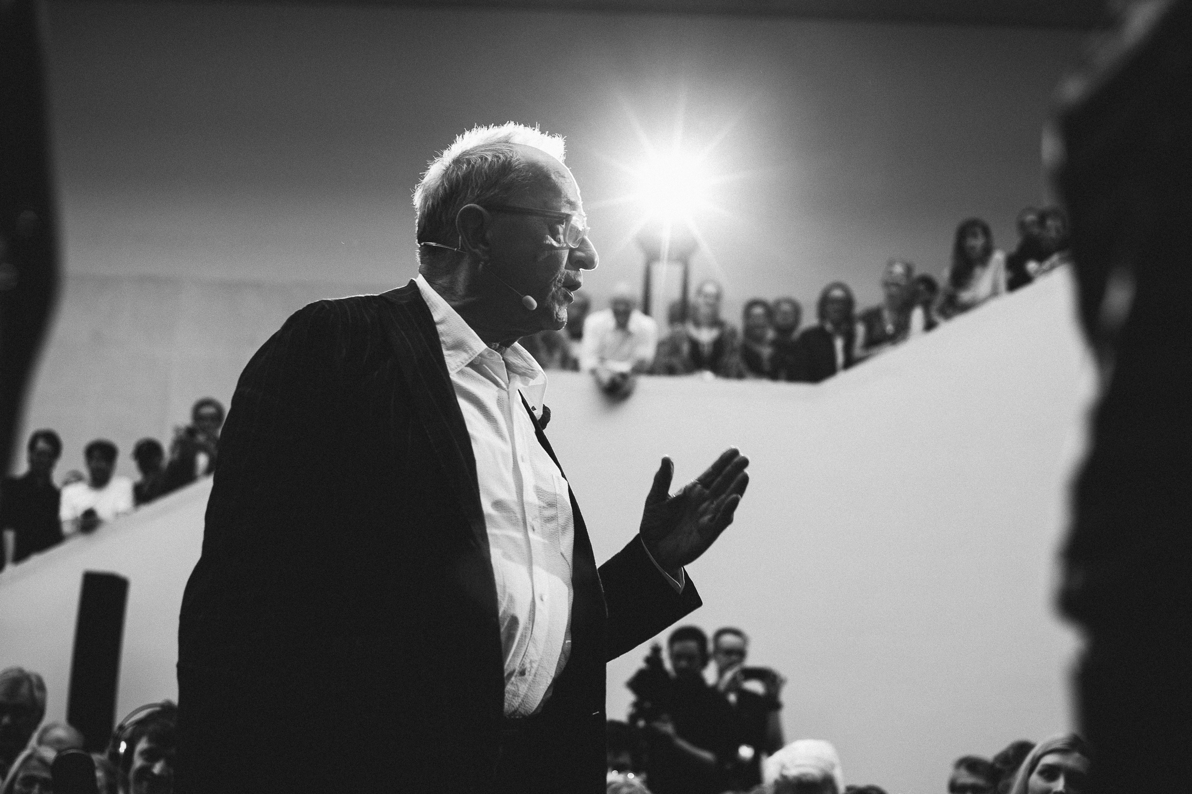 Das schwarz-weiß Foto zeigt Kasper König im Profil. Er steht im weißen Museumsfoyer. Im Hintergrund sieht man einen Kamerablitz.