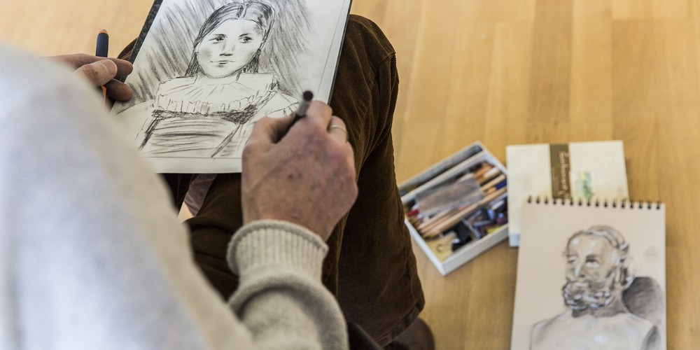 Person zeichnet mit Bleistift ein Gesicht