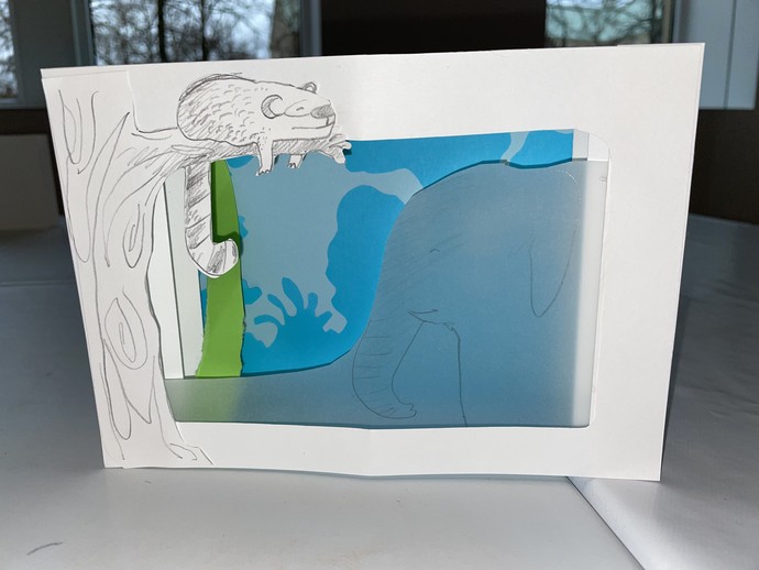 Ein Landschaft mit Tieren in einem aus Papier gefalteten Kasten.