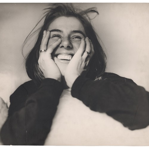 Eine Frau stützt ihren Kopf lachend in den Händen.