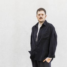 A man standing in front of a white wall.