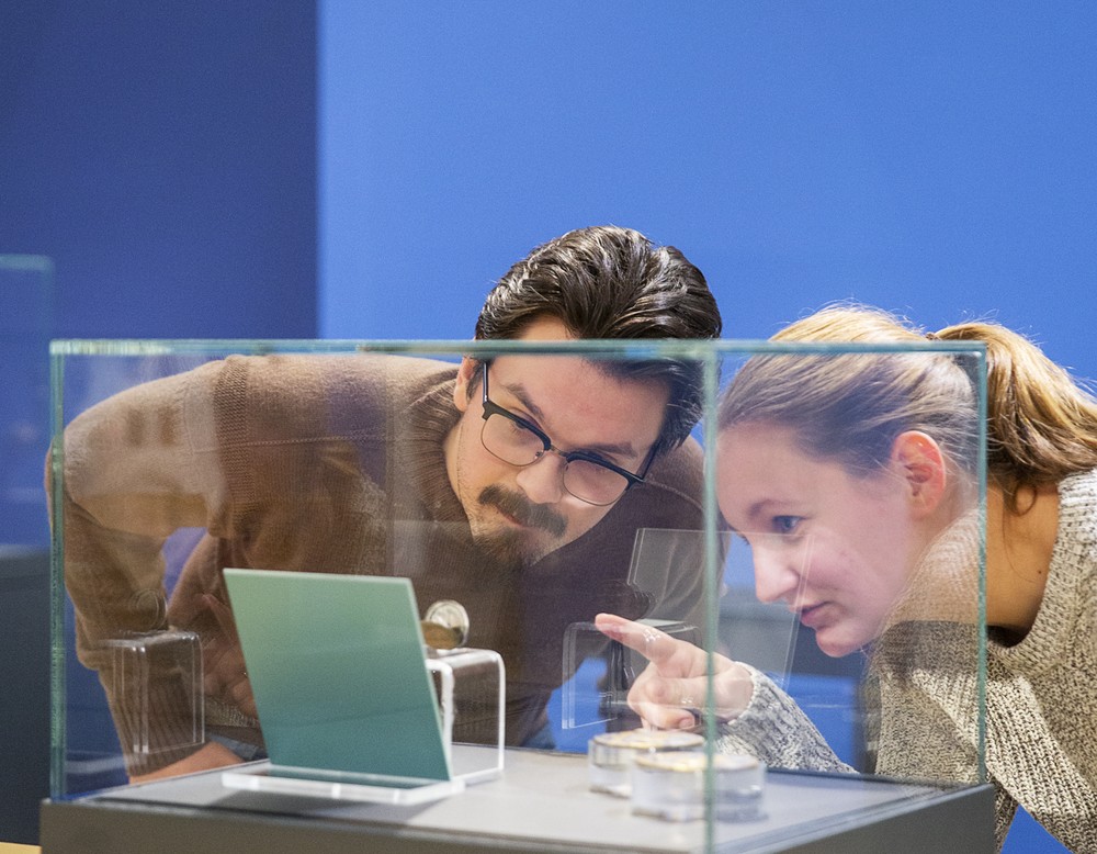 Zwei Personen schauen auf ein Objekt in einer Vitrine.