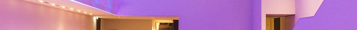 Viele Menschen befinden sich im pink beleuchteten, modernen Foyer des Museums.