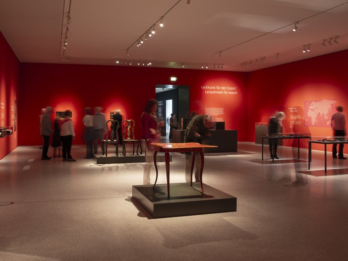 Das Bild zeigt eine Aufnahme aus der Ausstellung. Zu sehen ist ein roter Raum mit einem großen Objekt, das aussieht, wie ein Tisch. (vergrößerte Bildansicht wird geöffnet)