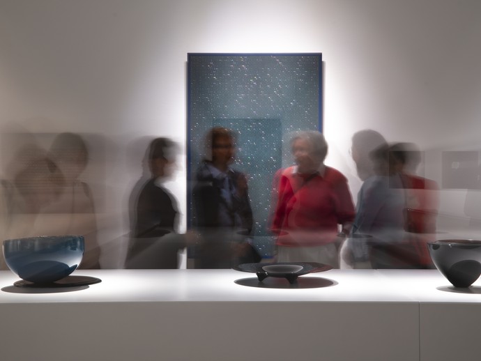 Das Bild zeigt eine Aufnahme aus der Ausstellung. Zu sehen ist ein weißer Raum mit einem modernen Objekt im Vordergrund. (vergrößerte Bildansicht wird geöffnet)
