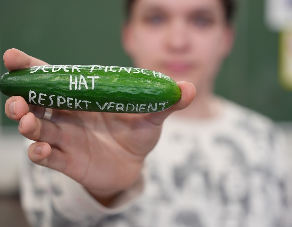 Schülerin zeigt beschriftete Gurke