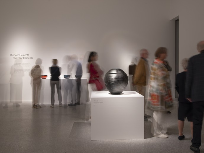 Das Bild zeigt eine Aufnahme aus der Ausstellung. Zu sehen ist ein weißer Raum mit einem großen, modernen, schwarzen Objekt. (vergrößerte Bildansicht wird geöffnet)