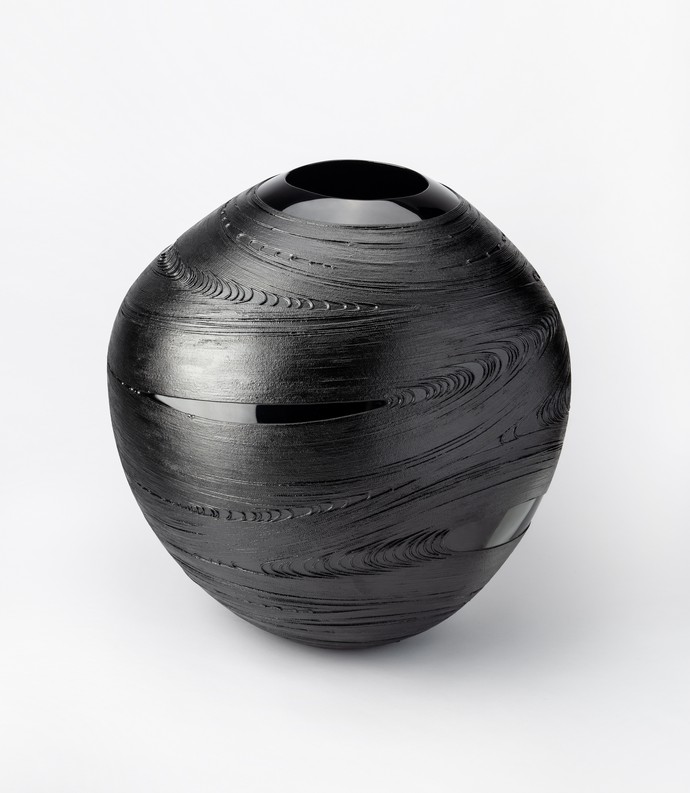 Schwarzes, bauchiges Lackobjekt mit geschwungenen Linien.