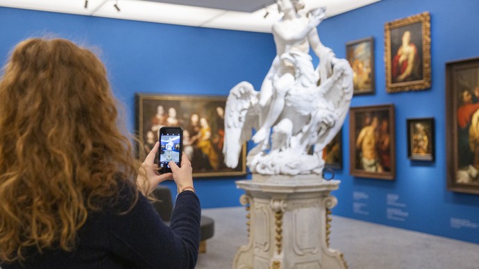 Eine Frau richtet ihr Handy auf eine Statue.