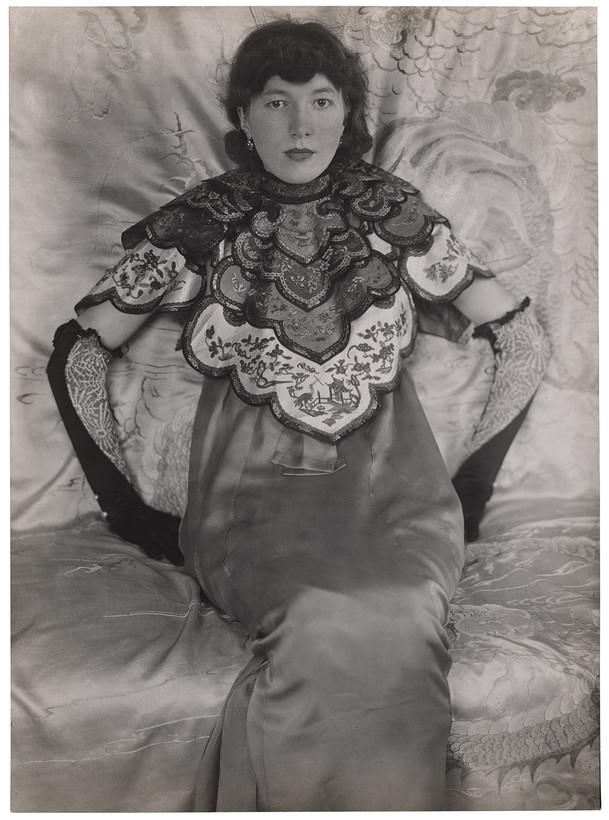 Dame in chinesischem Kleid auf einem Sitzmöbel mit Seidembezug